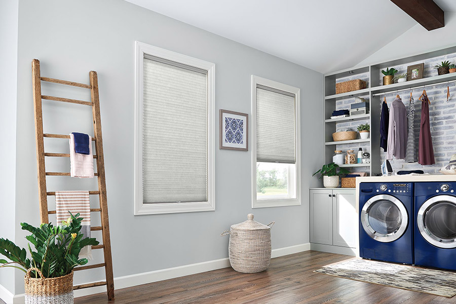 Gray cellular shades on windows in a gray laundry room